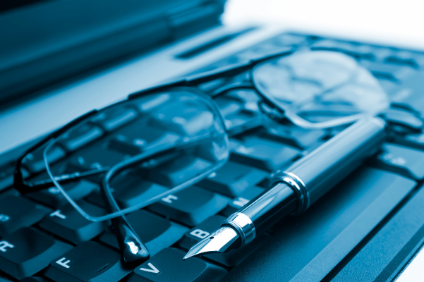 A pair of spectacles and a fountain pen on a laptop keyboard.